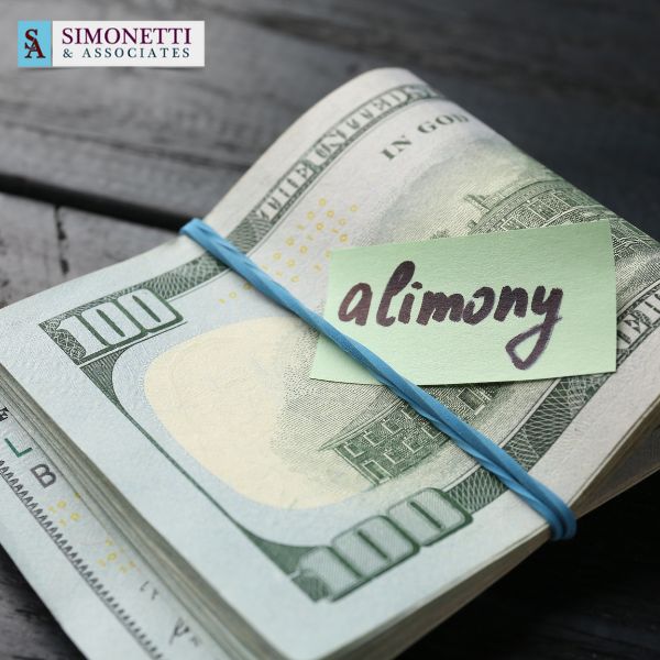 A stack of $100 bills wrapped with a blue rubber band and a note labeled "alimony," featuring a law firm logo in the corner, suggests guidance from a Huntington Divorce Lawyer.