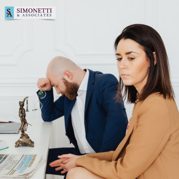 A woman sits in the foreground looking serious, while a man in a suit—perhaps a divorce lawyer in Huntington—sits at a desk behind her with his head resting on his hand. The Simonetti & Associates logo is visible.