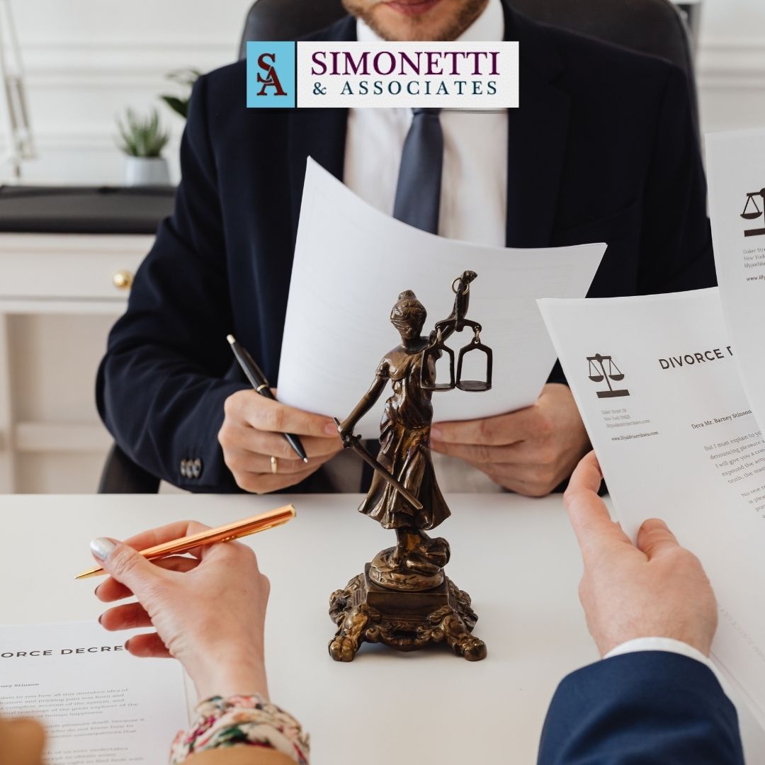 Two people review divorce documents across a desk with a Lady Justice statue; a Divorce lawyer in Huntington sits opposite them. A Simonetti & Associates logo is visible above.