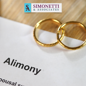 Two gold wedding rings rest on a document labeled "Alimony," with the Simonetti & Associates logo at the top, representing trusted guidance from an Alimony Lawyer in Long Island.